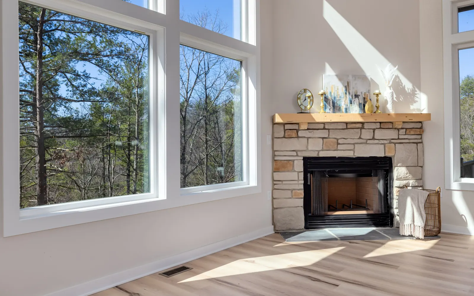A living room with a stone fireplace and tall windows